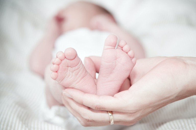 Mani che tengono piedi di neonato